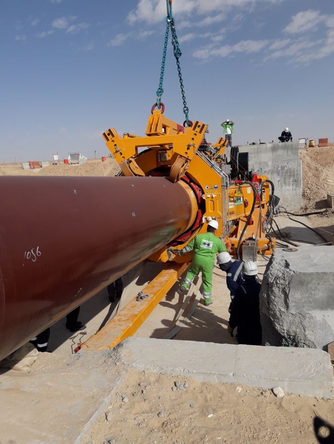 Crew guiding a steel pipeline into the Direct Pipe thruster in the desert